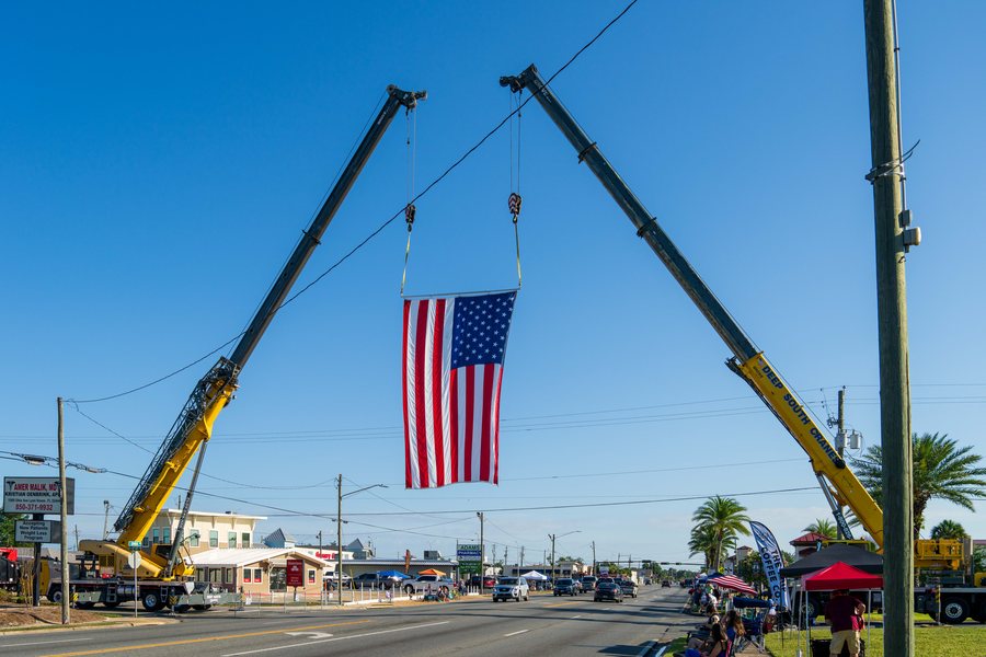 A large American flag hung between two cranes over the Lynn Haven Fourth of July parade route