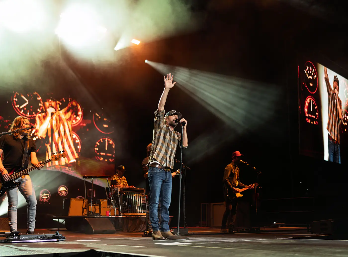 Dierks Bentley reaching up under a single spotlight over the crowd