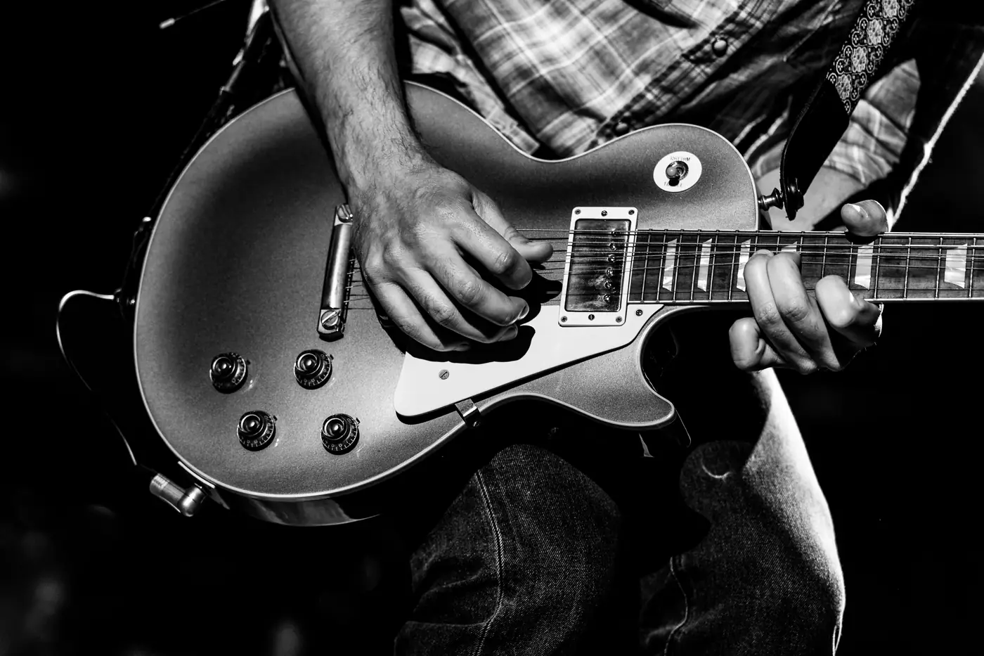 Hands on a Les Paul guitar, black and white detail