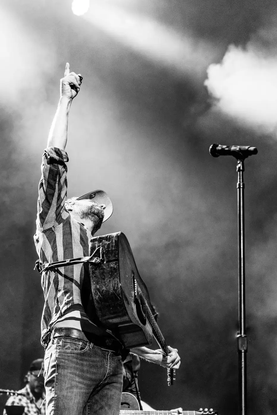 Dierks Bentley pointing skyward in stage smoke, black and white