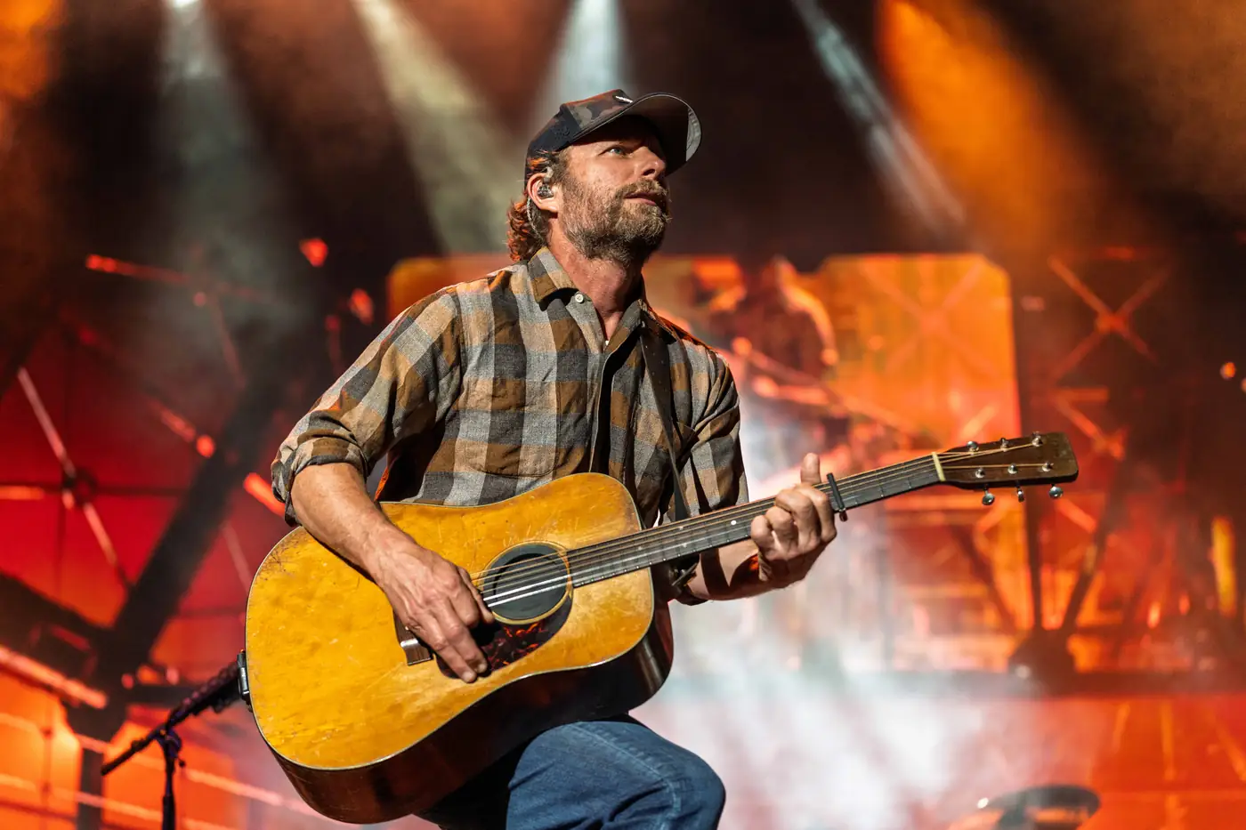 Dierks Bentley crouched low with guitar against the orange stage rig
