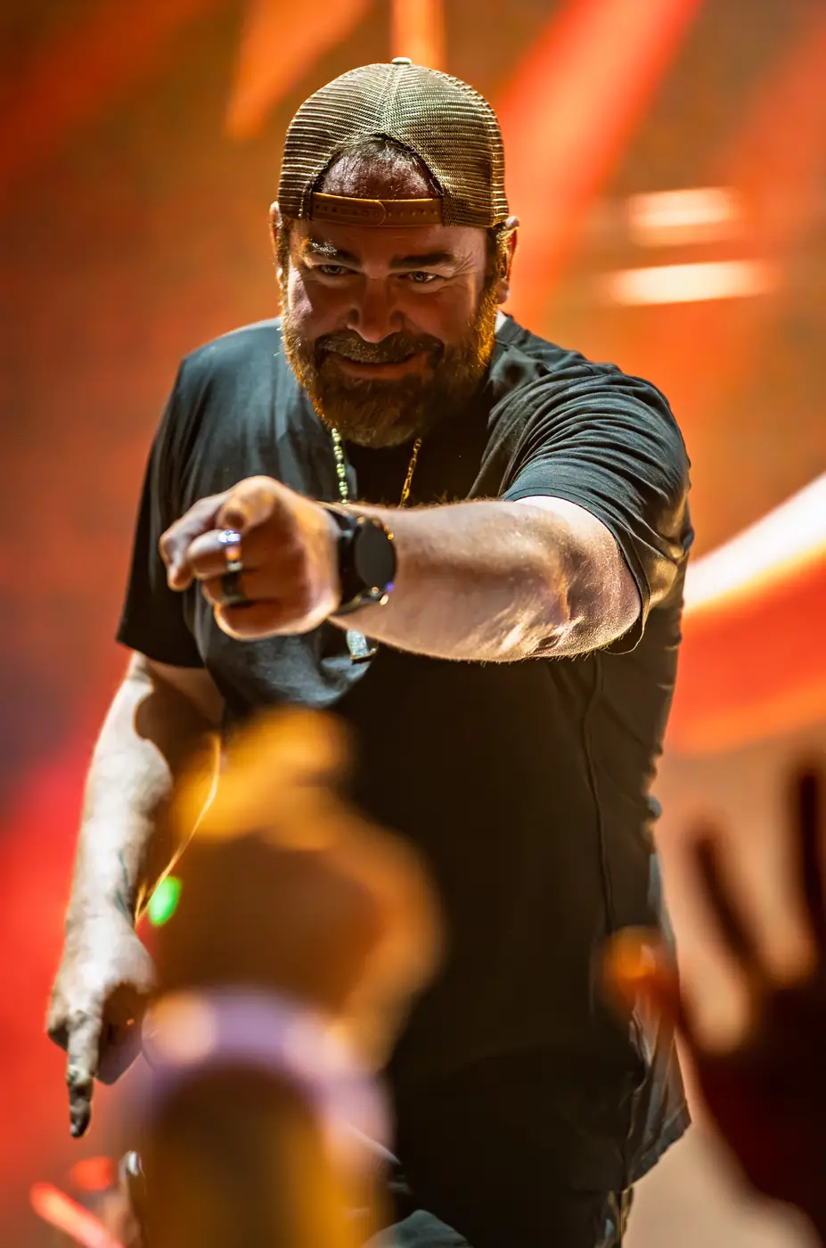Lee Brice pointing into the crowd in orange light