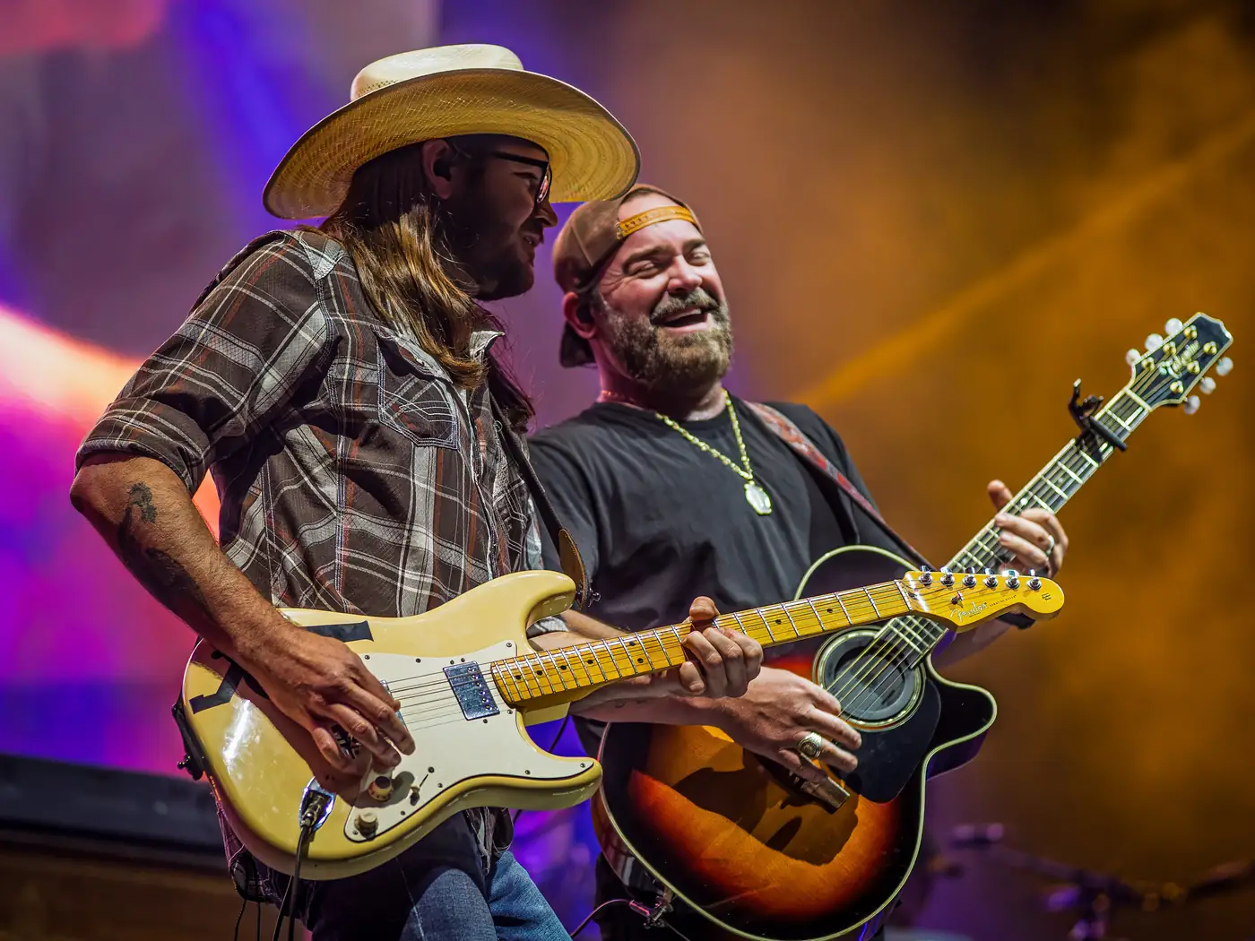 Lee Brice laughing with his guest guitarist mid-song