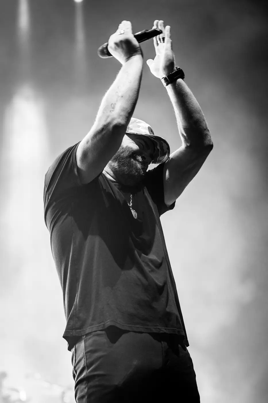 Lee Brice with arms crossed overhead at the mic, black and white