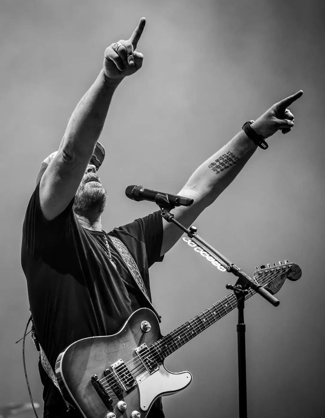 Lee Brice pointing skyward at the mic, black and white