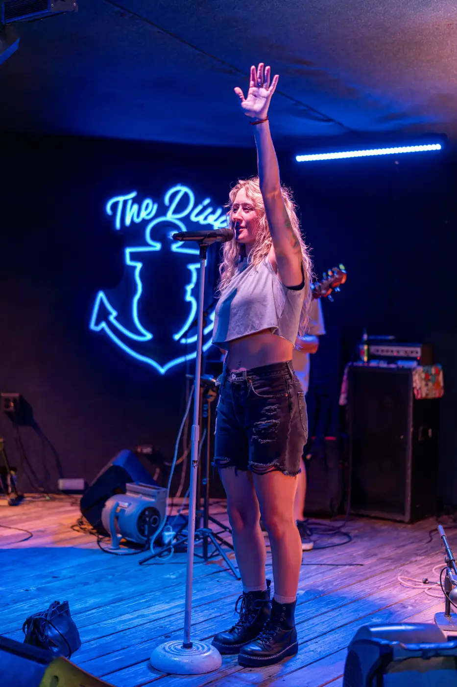 Scratch 2020 lead singer with arm raised under neon light