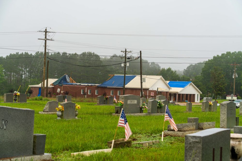 Coaltown Baptist Church under storm tarps, with the cemetery in the foreground